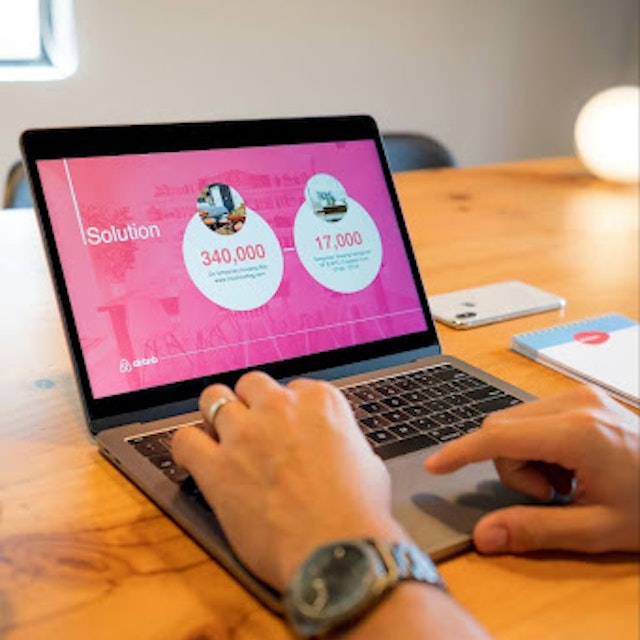 Pair of hands clicking away on a laptop. Laptop screen shows a slide deck.